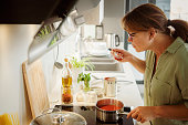 Woman cooking and tasting tomato sauce