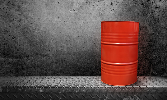 Orange oil barrels on steel plate with cement wall background