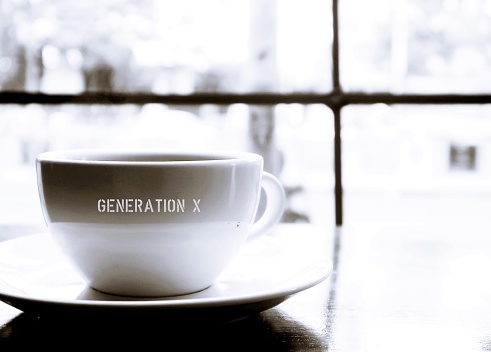 Black and white coffee cup with text GENERATION X on cafe table - concept of people who born 1965-1979 or in midlife 40-56 yrs old, still digitally savvy