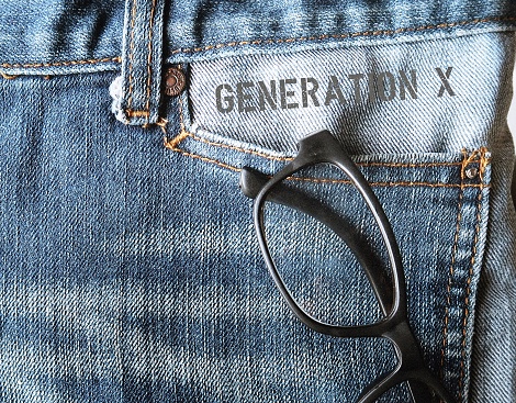 Jeans with reading glasses and text GENERATION X, concept of demographic group people who born 1965-1979 now in midlife 40-56 yrs old, prefer work life balance and still digitally savvy