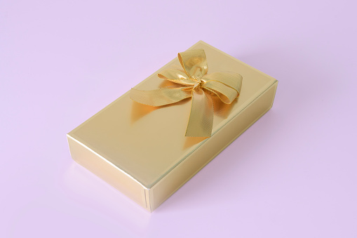 Gift box with golden ribbon and bow on pink background. mockup