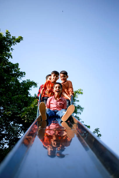Group of elementary age children's of Indian ethnicity having fun on slide in the park together portrait close up with copy space.