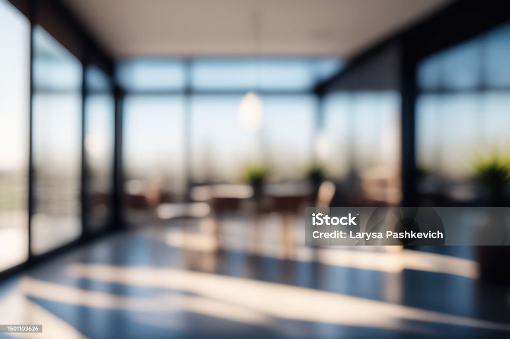 Defocused background image of a spacious hallway in a modern office. Beautiful blurred background of a light modern office interior with panoramic windows and beautiful lighting. Office Stock Photo