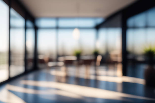 Defocused background image of a spacious hallway in a modern office. Beautiful blurred background of a light modern office interior with panoramic windows and beautiful lighting. desk stock pictures, royalty-free photos & images