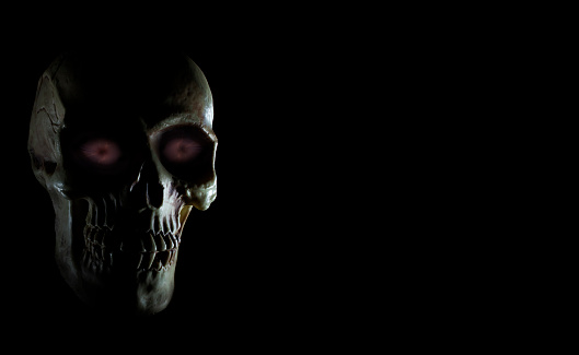 Purple glowing eyes on a human skull with copy space