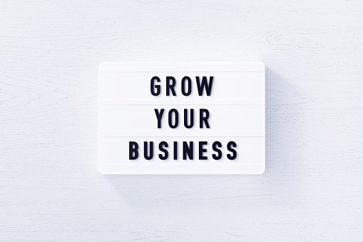 Grow your business written white lightbox on white wood background. Horizontal composition with copy space.