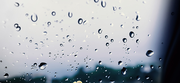 Raindrops on glass surface. Full frame view with cloudy sky background. Galicia, Spain.