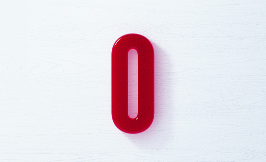 Zero  made of red glass on white wood background. Horizontal composition with copy space.