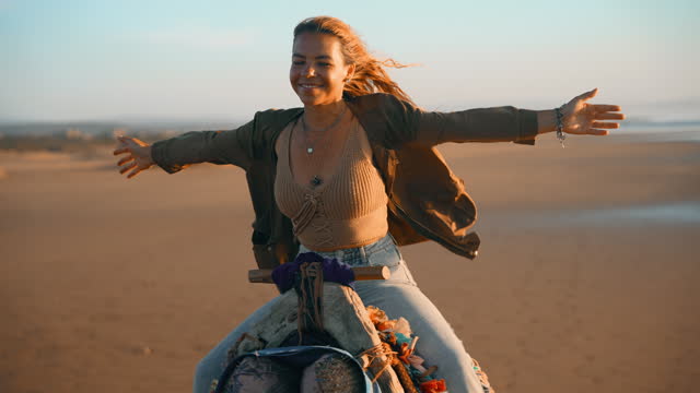 SLO MO Woman tourist enjoying camel ride with arms outstretched at beach