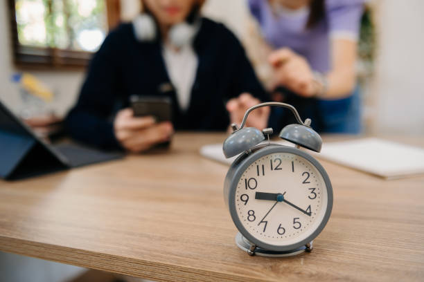 istock Alarm clock on the desk. Business working in modern office building or home at night using laptop. 1501111126