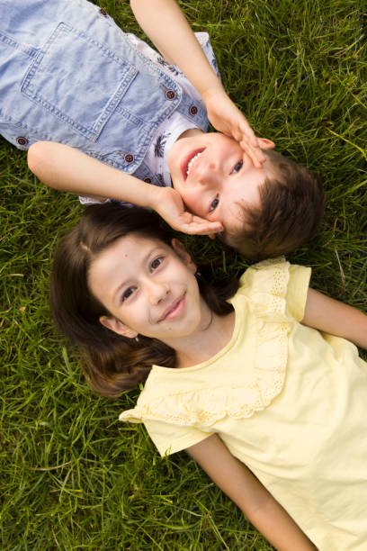 Boy and girl lying on green grass stock photo