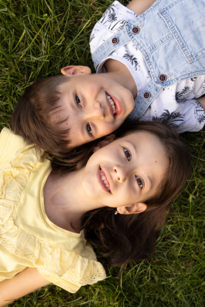 Boy and girl lying on green grass stock photo