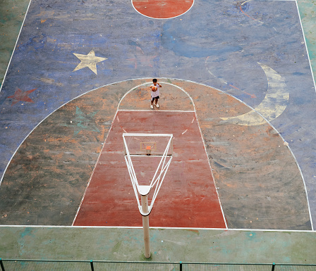 Faded Colorful painted basketball court in Singapore HDB estate in Toa Payoh with person shooting a free throw