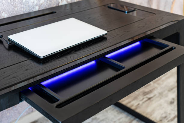 istock Top view of empty open wooden drawer office table with blue lightning. Modern office table with light 1501114441
