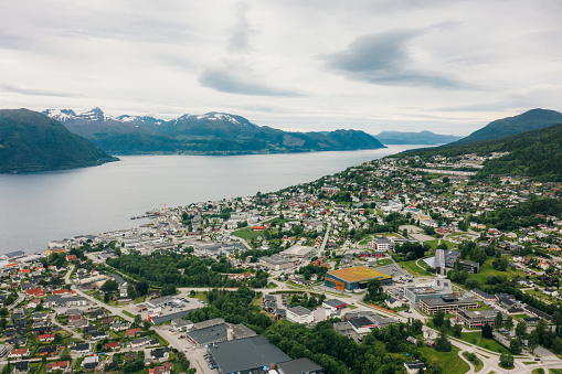 Drone high-angle photo of Volda city with two stadiums surrounded by the scenic green hills, snowcapped mountains and the lake in Western Norway, Scandinavia