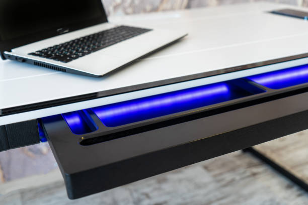 istock Top view of open wooden drawer white office table with blue lightning. Modern office table with light 1501115139