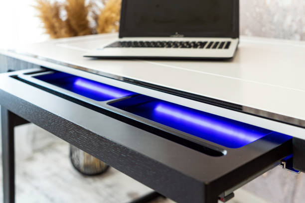 istock Top view of open wooden drawer white office table with blue lightning. Modern office table with light 1501115167