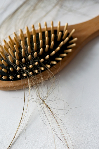 Tangled hair and comb on white background.