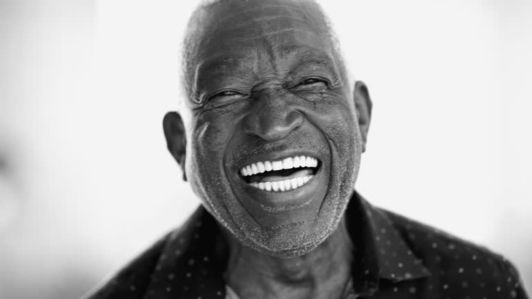 One joyful Brazilian senior black man close-up face laughing and smiling in monochrome black and white photography