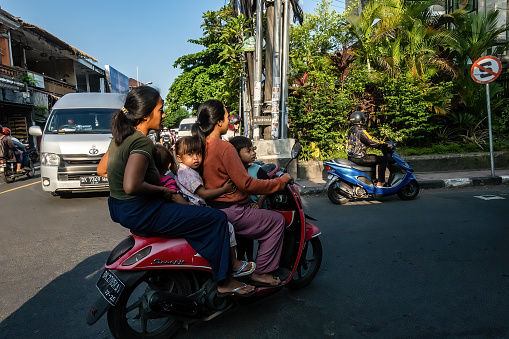 Ubud, Bali, Indonesia May 24, 2023 Two women and two kids share a scooter on a busy street.