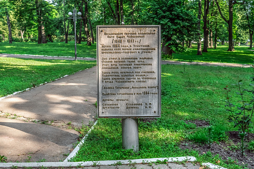 Trostyanets, Sumy Oblast, Ukraine - June 18, 2023: Tourist info board with information about the Monument to Tchaikovsky in the Trostyanets central park. Stone slab with text among summer greenery