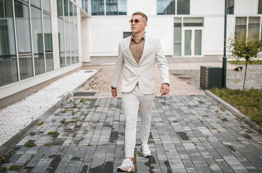 Portrait of a handsome young man in a white suit posing for the camera