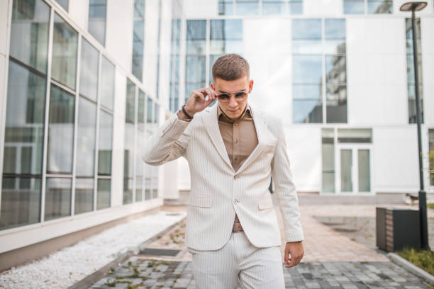 Portrait of a handsome young man in a white suit posing for the camera