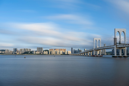 The sunny side view of the cross sea bridge and the high-rise buildings of the city