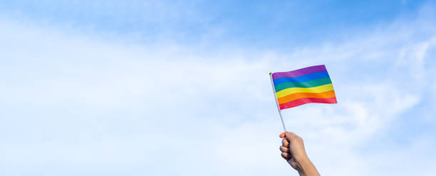 istock rainbow gay flag in hand waving against clear blue sky space banner 1501148355