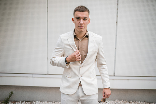 Portrait of a handsome young man in a white suit posing for the camera