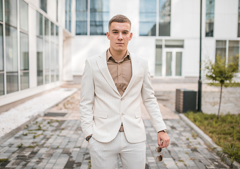 Portrait of a handsome young man in a white suit posing for the camera