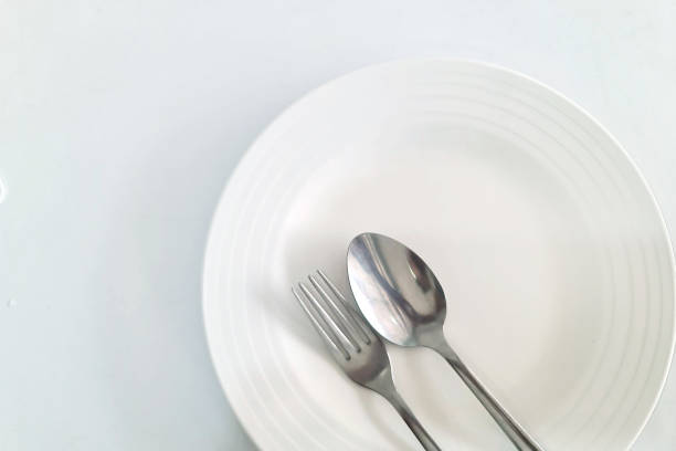istock Spoon and fork in a white plate; White table in the restaurant with empty dish 1501158951
