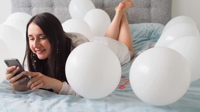 Woman lying on bed with decorations with balloons for Birthday party