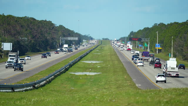 Mulitlane american highway with rapid driving cars during rush hour in Florida. Rising heat gives a shimmering mirage effect over the pavement. View from above of USA transportation infrastructure
