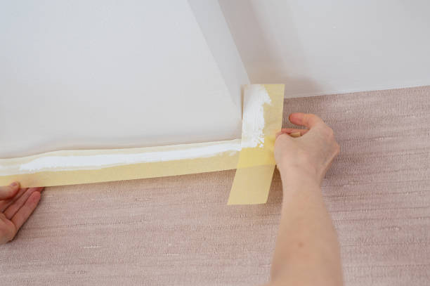 close-up of female hands remove masking tape - paint preparation adhesive tape indoors imagens e fotografias de stock