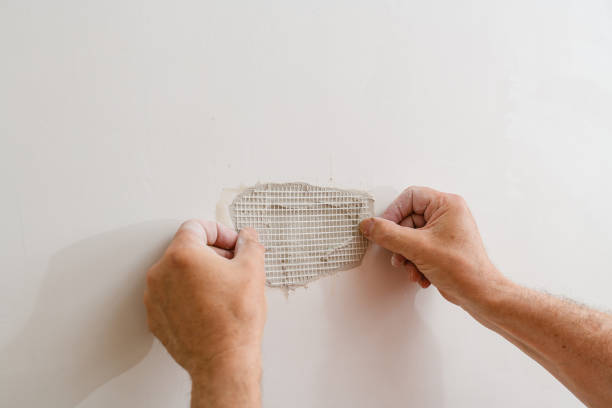 A handyman is repairing a hole in the drywall in the wall. Repairing holes in drywall. A handyman is repairing a hole in the drywall in the wall. painted drywall texture stock pictures, royalty-free photos & images
