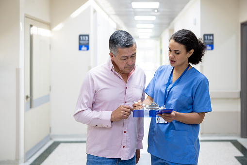 Latin American nurse talking to a patient at the hospital explaining his medical record - healthcare and medicine concepts