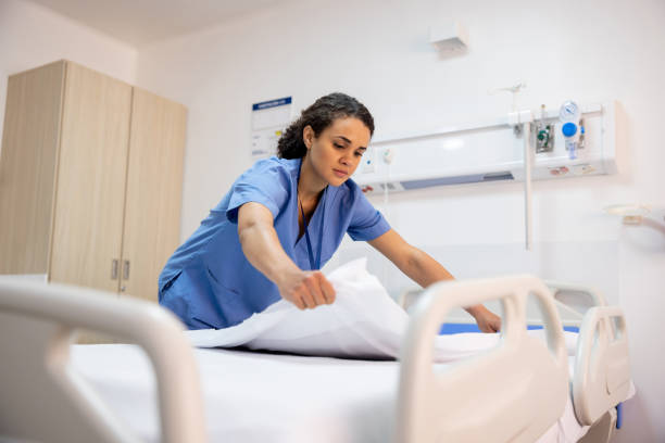 Latin American nurse making a bed in a hospital room - healthcare and medicine concepts