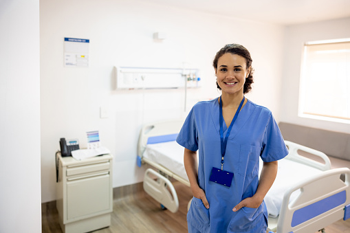 Portrait of a Latin American nurse working at a hospital and smiling in a room - healthcare and medicine concepts