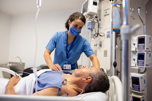 Nurses in intensive care unit of hospital checking vitals of hospitalized female patient. ICU