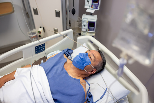 Hospitalized man wearing a face mask while lying on a bed at the ICU