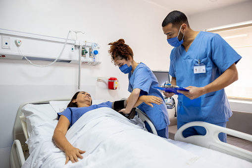 Latin American nurses taking the blood pressure of a patient at the ICU - emergency room concepts