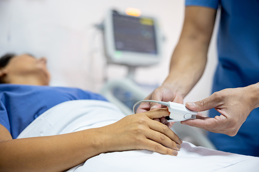 Close-up on a nurse placing a pulse oximeter on a female patient at the hospital - Intensive Care Unit concepts