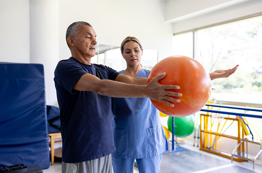 Latin American man doing physical therapy at a rehabilitation center with the guidance of his physical therapist