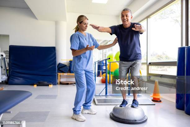 Man Doing Physical Therapy Exercises Using A Balance Ball Stock Photo - Download Image Now