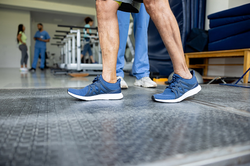 Close-up on a man in physical therapy taking his first steps - healthcare and medicine concepts