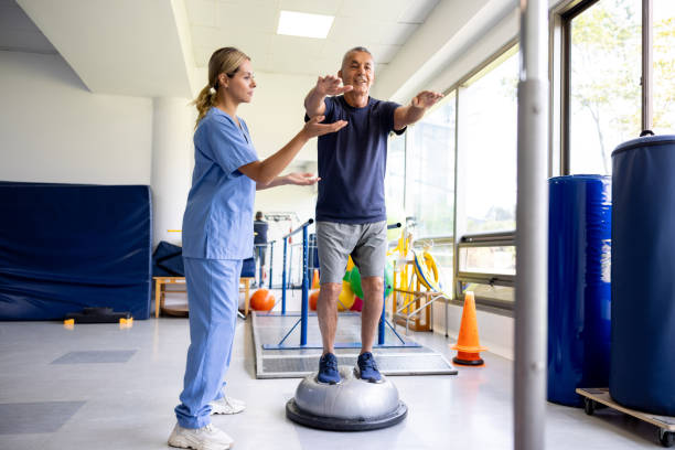 istock Man doing exercises using a balance ball with the help of his physical therapist 1501185778