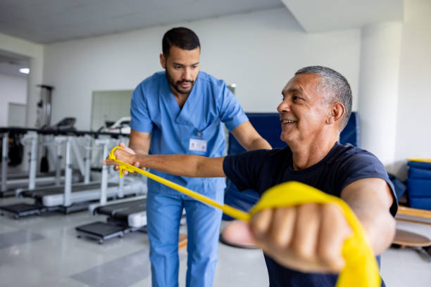 hombre haciendo ejercicios de fisioterapia usando una banda elástica - occupational therapy fotografías e imágenes de stock