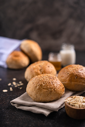 Fresh whole grain brown buns with sesame seeds on rustic background. Healthy artisan bread.