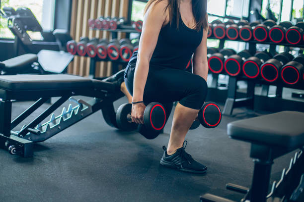 istock Young woman doing squats with dumbbell in gym 1501188482